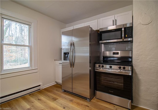 kitchen with light wood finished floors, tasteful backsplash, stainless steel appliances, a baseboard heating unit, and white cabinetry