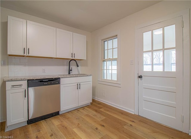 kitchen featuring light wood-style flooring, a sink, white cabinetry, light stone countertops, and dishwasher