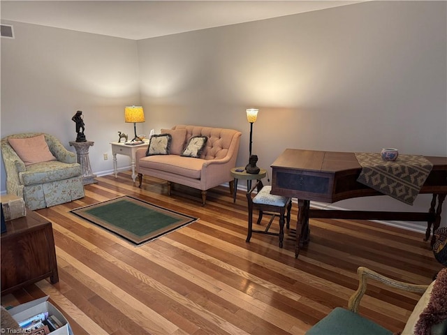 living area featuring visible vents and wood finished floors