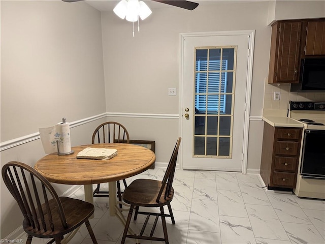 dining area featuring a ceiling fan, baseboards, and marble finish floor