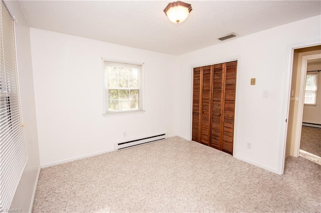 unfurnished bedroom featuring a baseboard radiator, carpet flooring, a closet, and multiple windows