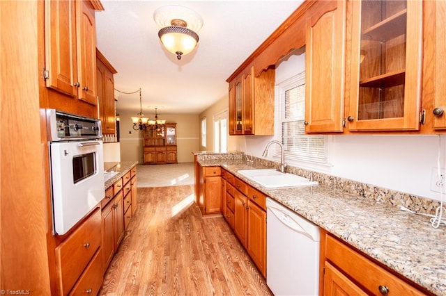 kitchen featuring sink, decorative light fixtures, light hardwood / wood-style flooring, white appliances, and light stone countertops