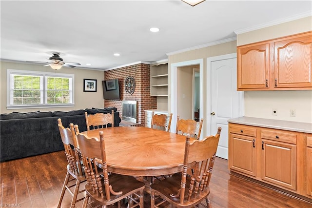 dining space featuring crown molding, ceiling fan, a brick fireplace, dark wood-style floors, and recessed lighting