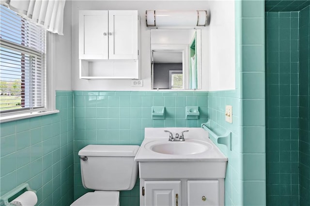 bathroom with tile walls, toilet, vanity, and wainscoting