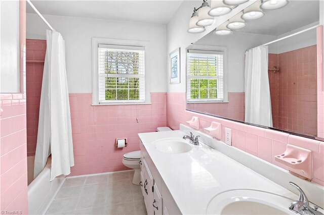 full bath featuring tile walls, a wealth of natural light, tile patterned floors, and a sink