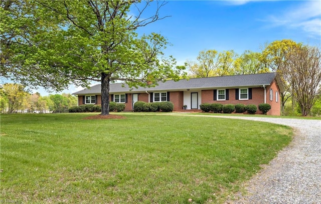 single story home featuring brick siding, gravel driveway, and a front lawn