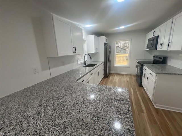 kitchen featuring dark stone counters, white cabinetry, sink, and black appliances