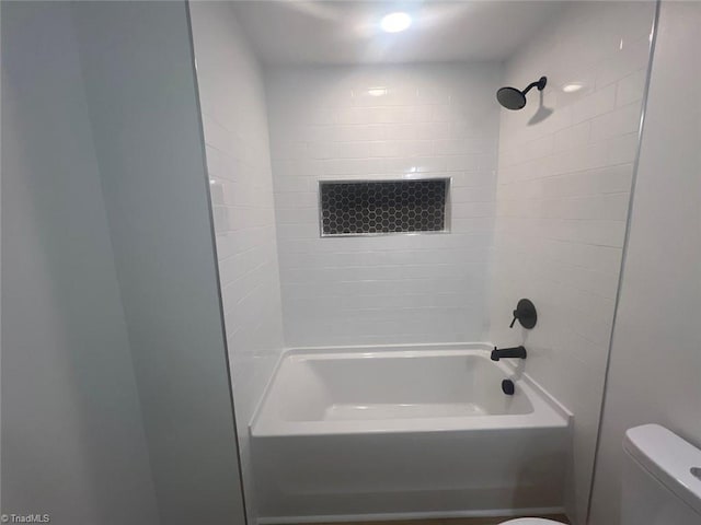 bathroom featuring tiled shower / bath and toilet