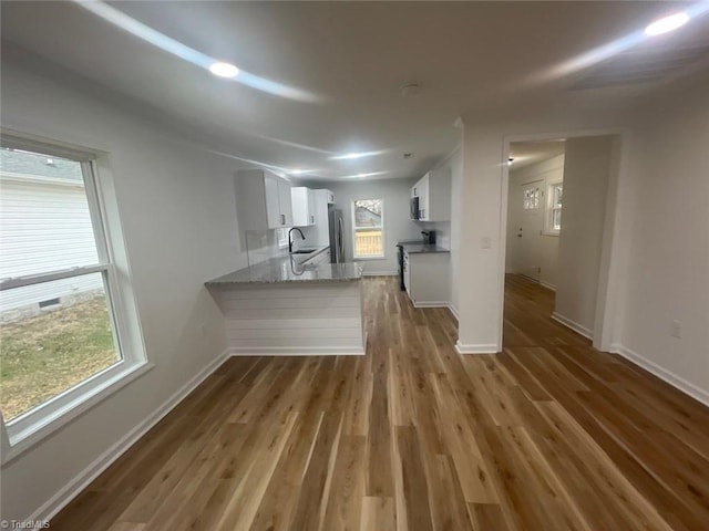 kitchen featuring sink, stainless steel appliances, dark wood-type flooring, kitchen peninsula, and white cabinets