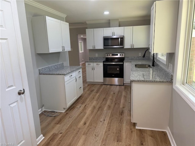 4115 Rose Lake Dr, Greensboro, NC 27407 - kitchen with stainless steel appliances, a sink, crown molding, light wood-style flooring, and white cabinetry