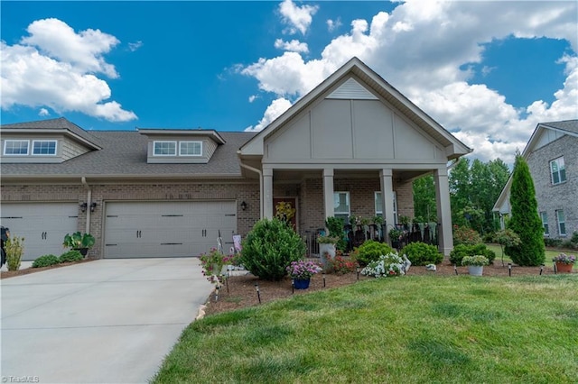 view of front of home with brick siding, covered porch, a front yard, a garage, and driveway