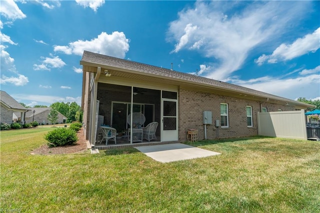 rear view of house featuring brick siding, a lawn, fence, and a sunroom