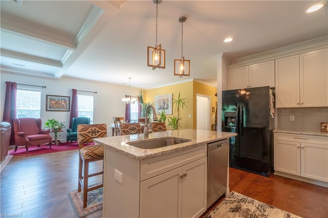 kitchen featuring black fridge with ice dispenser, decorative light fixtures, sink, dark hardwood / wood-style floors, and a center island with sink