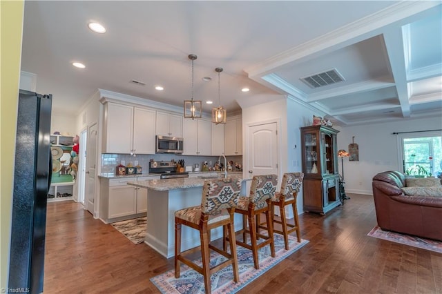 kitchen with visible vents, coffered ceiling, open floor plan, stainless steel appliances, and a sink