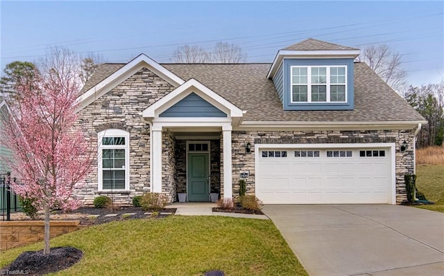 view of front of property with an attached garage, a shingled roof, driveway, stone siding, and a front yard