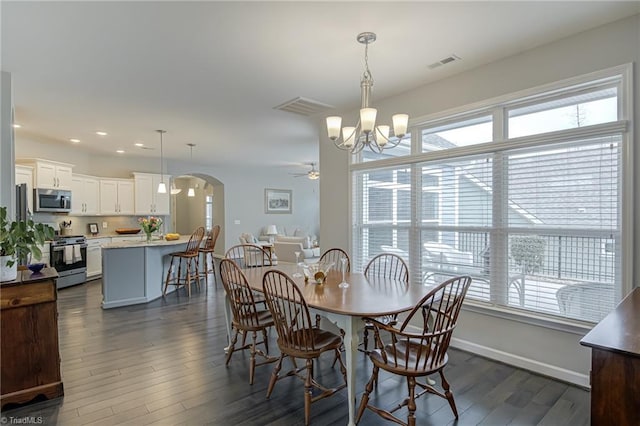 dining space with dark wood-style floors, arched walkways, visible vents, baseboards, and ceiling fan with notable chandelier