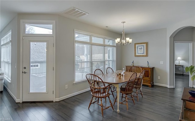 dining space with arched walkways, a notable chandelier, visible vents, baseboards, and dark wood-style floors