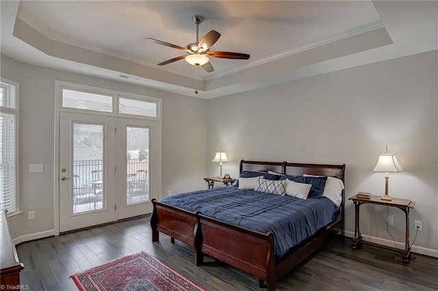 bedroom with access to outside, a raised ceiling, and wood finished floors