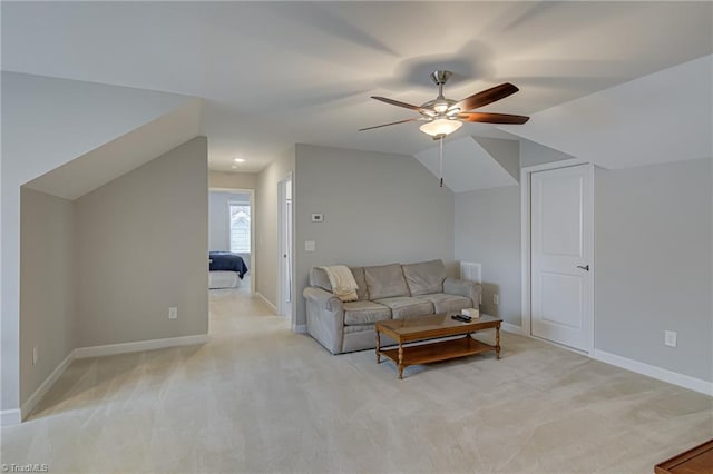 living area featuring lofted ceiling, ceiling fan, baseboards, and light colored carpet