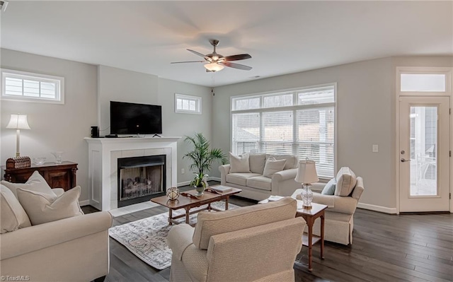 living room with a ceiling fan, a fireplace, dark wood finished floors, and baseboards