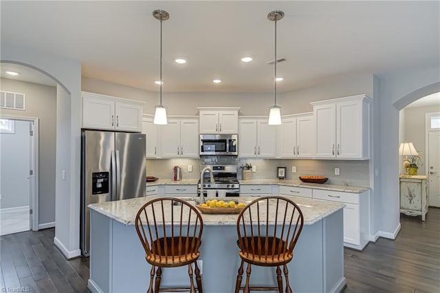 kitchen featuring arched walkways, visible vents, backsplash, appliances with stainless steel finishes, and white cabinets