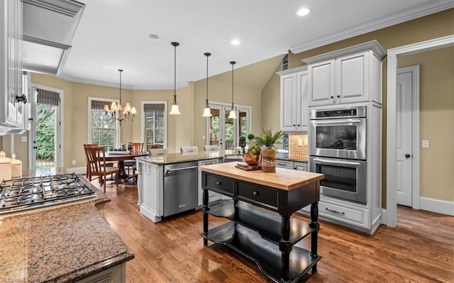 kitchen with a peninsula, dark wood-style flooring, stainless steel appliances, hanging light fixtures, and a chandelier