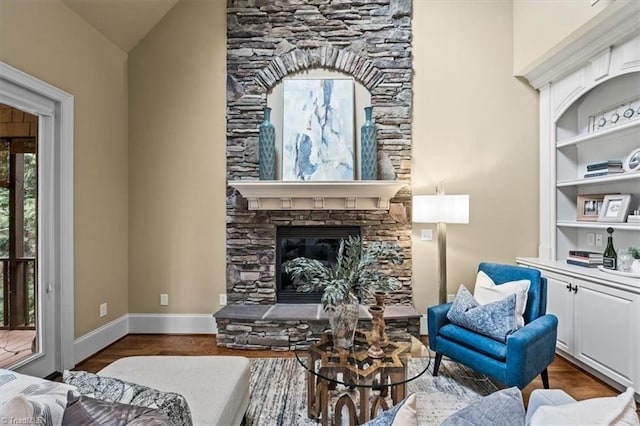 sitting room with a fireplace, baseboards, and wood finished floors