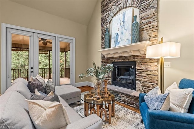 living area featuring lofted ceiling, wood finished floors, french doors, a fireplace, and baseboards