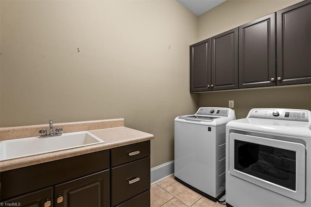 clothes washing area with light tile patterned floors, baseboards, cabinet space, a sink, and washer and dryer