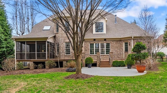 rear view of property with a patio, a lawn, brick siding, and a sunroom