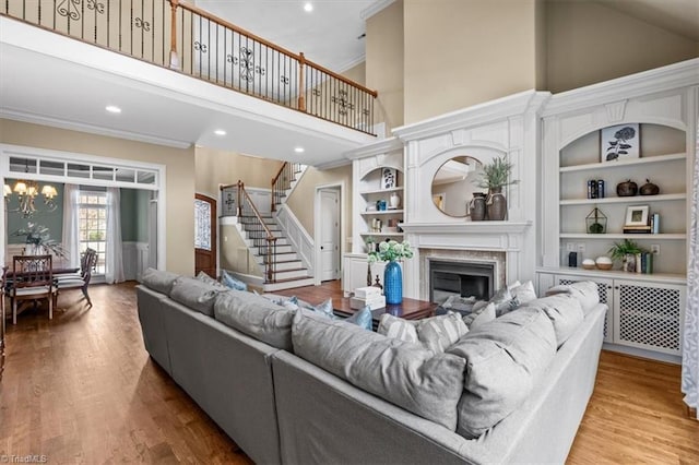 living room with stairway, ornamental molding, a fireplace, and wood finished floors