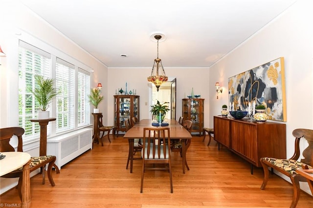 dining area featuring radiator heating unit, crown molding, and light hardwood / wood-style flooring