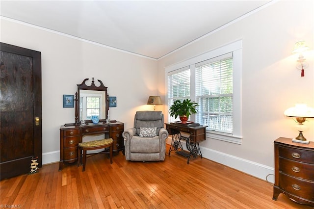 living area featuring light wood-type flooring, ornamental molding, and a healthy amount of sunlight