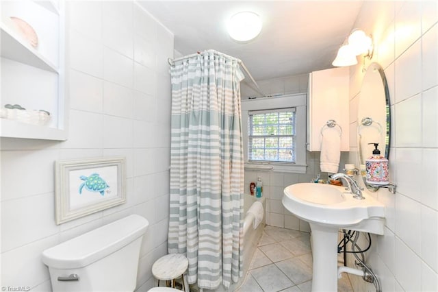 bathroom with tile patterned flooring, shower / bath combo, toilet, and tile walls