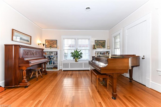 miscellaneous room featuring hardwood / wood-style flooring, crown molding, and radiator