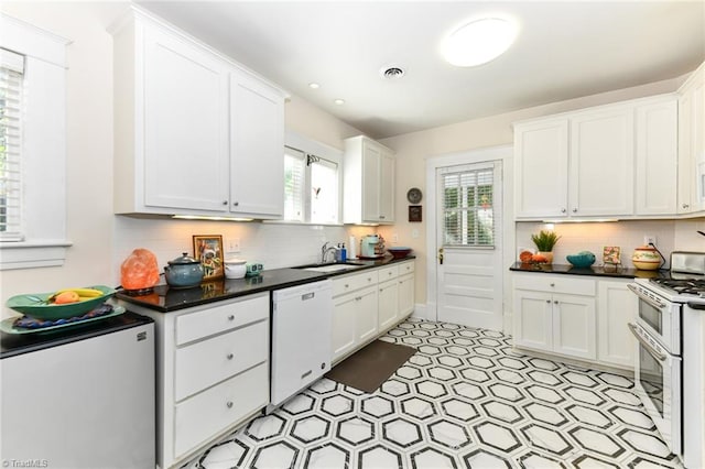 kitchen featuring white dishwasher, backsplash, white cabinetry, fridge, and stainless steel range oven