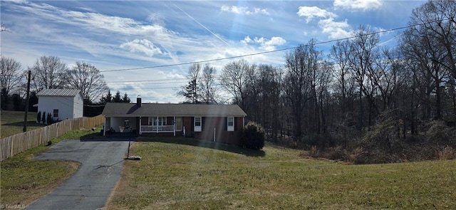 view of front facade featuring driveway, a porch, a front yard, and fence