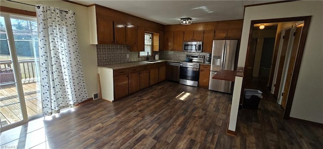 kitchen with tasteful backsplash, appliances with stainless steel finishes, sink, and dark hardwood / wood-style flooring