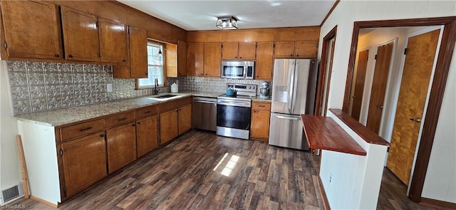 kitchen with tasteful backsplash, sink, dark wood-type flooring, and stainless steel appliances