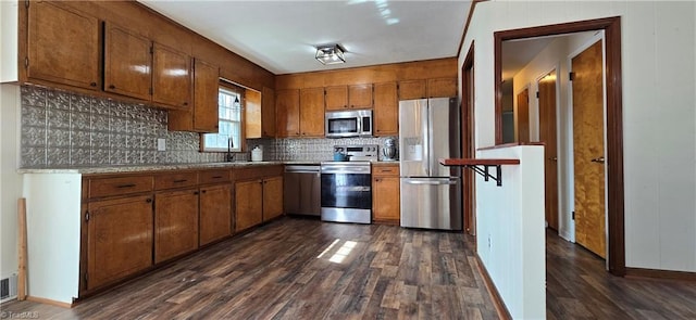 kitchen with appliances with stainless steel finishes, dark wood-type flooring, sink, and backsplash