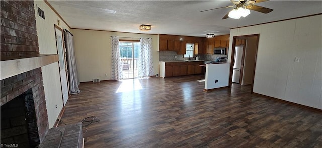 kitchen featuring a brick fireplace, ornamental molding, dark hardwood / wood-style flooring, ceiling fan, and stainless steel appliances