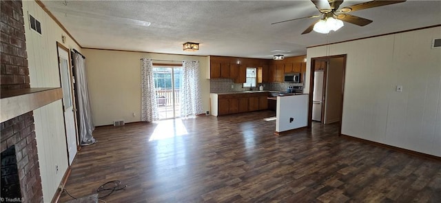 kitchen featuring stainless steel appliances, ornamental molding, a brick fireplace, and dark hardwood / wood-style flooring