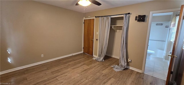 unfurnished bedroom with ceiling fan, ensuite bathroom, hardwood / wood-style floors, and a closet