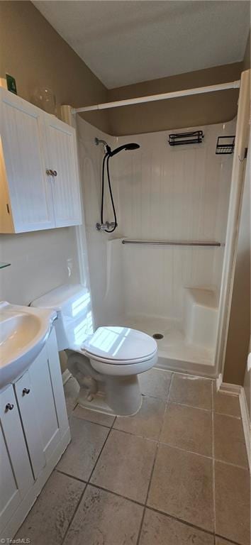 bathroom featuring vanity, a shower, tile patterned floors, and toilet