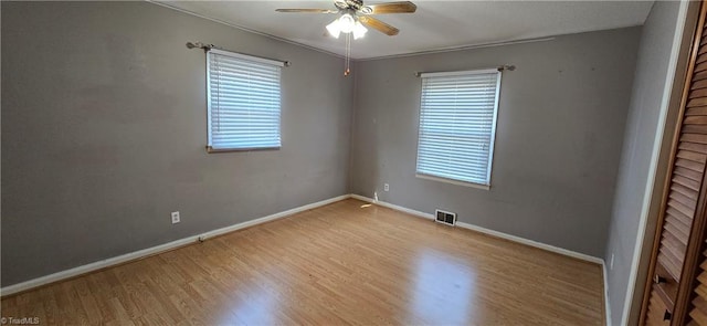 empty room with ceiling fan, a wealth of natural light, and light wood-type flooring