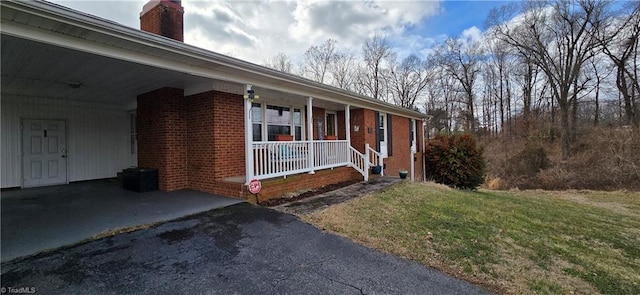 view of side of home with a carport, a yard, and covered porch