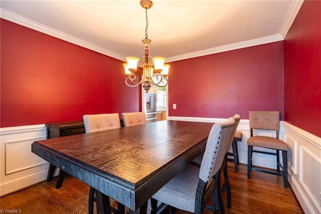 dining space featuring dark wood-type flooring, a wainscoted wall, and crown molding