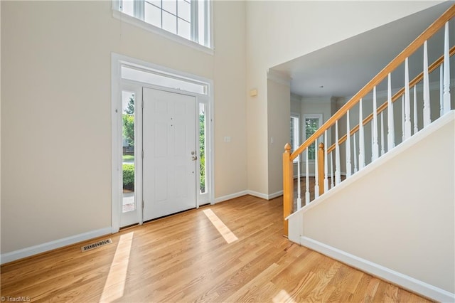 foyer with healthy amount of natural light, a high ceiling, baseboards, wood finished floors, and stairway