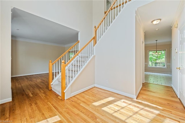 staircase with crown molding, wood finished floors, and baseboards