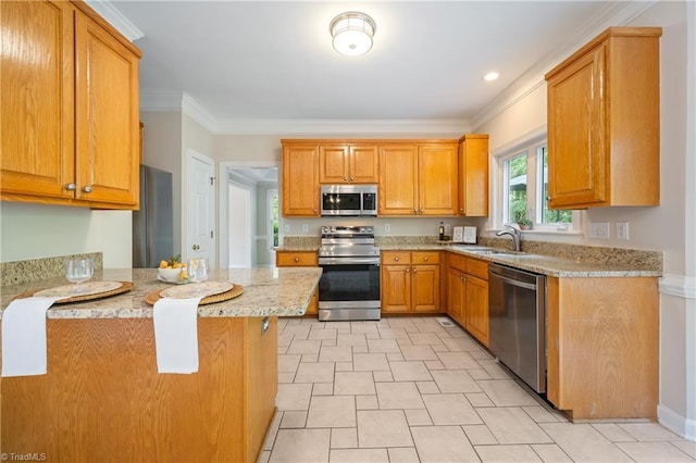 kitchen featuring stainless steel appliances, a sink, light stone counters, a peninsula, and crown molding